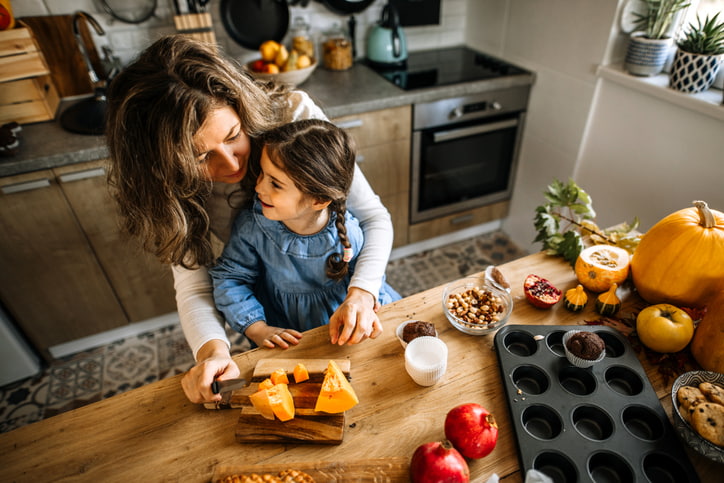Woman and daughter cooking with pumpkin in cozy kitchen